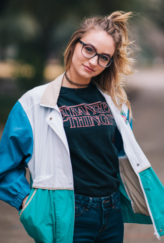 Modetrend 2020: Junge Frau mit Stranger Things Pirntshirts, Vintage-Blouson und Tattoo-Kette
