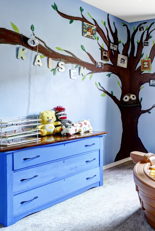 Kinderzimmer mit blauer Tapete und großem Baum
