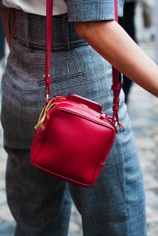 Frau in Karohosen und roter Handtasche