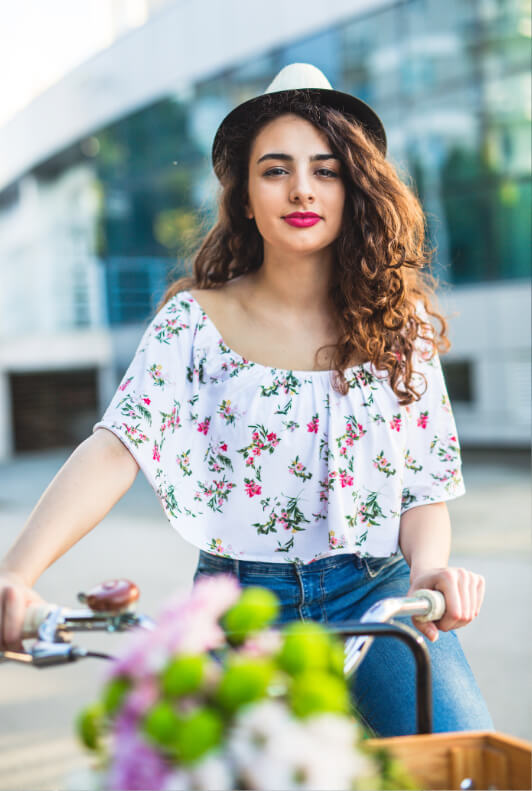 Junge Frau im floralen Rüschentop auf Fahrrad