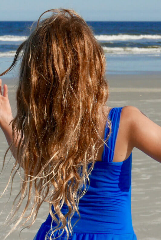 Frau mit Beach Waves und blauem Kleid am Strand