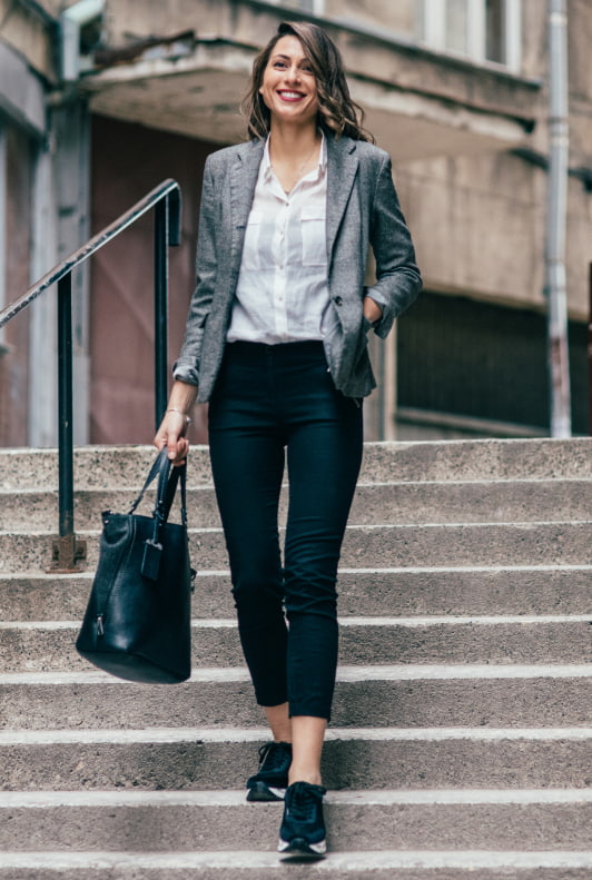 Street Style: Frau mit grauem Blazer, schwarzer Hose und schwarzen Sneakern