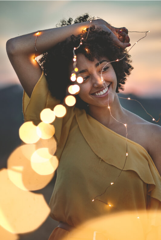 Junge, lächelnde Frau mit Afro und Lichterkette