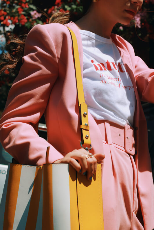 Frau in rosa Power-Suit und gelber Tasche