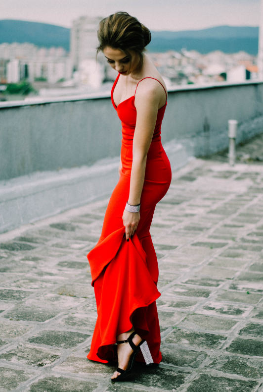 Frau mit langem roten Abendkleid und schwarzen Stilettos