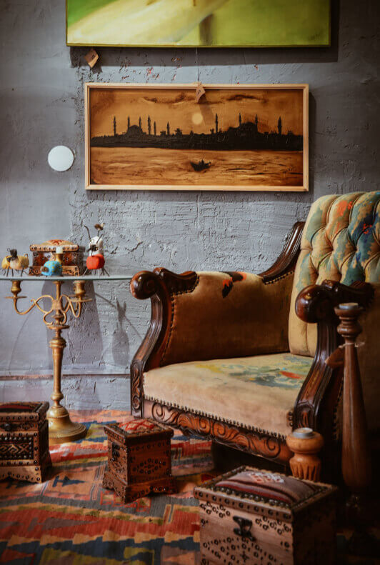 Wohnzimmer im Vintage-Stil mit altem Sessel, Truhen, Teppich und Wanddeko  