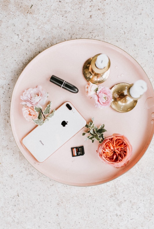 Rosa Tablett mit Kerzen, Blumen, Lippenstift und Smartphone