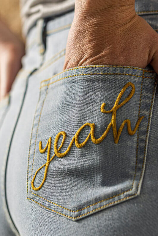 Gelber Yeah-Schriftzug auf Jeanshose von Bleed