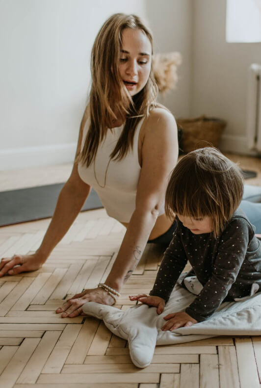 Frau und Kind machen zusammen auf dem Boden Yoga