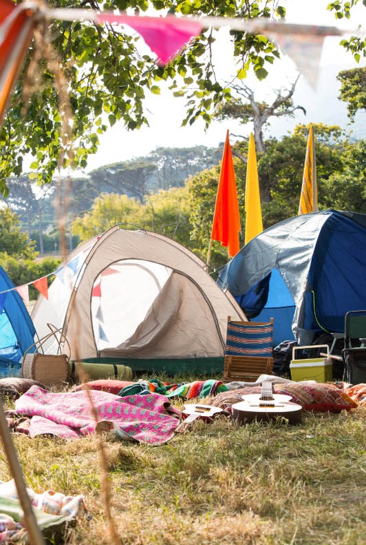 Zeltplatz auf einem Festivalgelände mit Decken, Fahnen und Klappstuhl