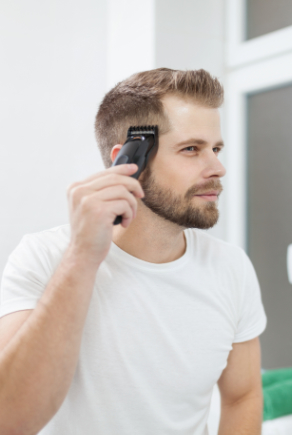 Mann rasiert sich die Haare vor einem Spiegel selber